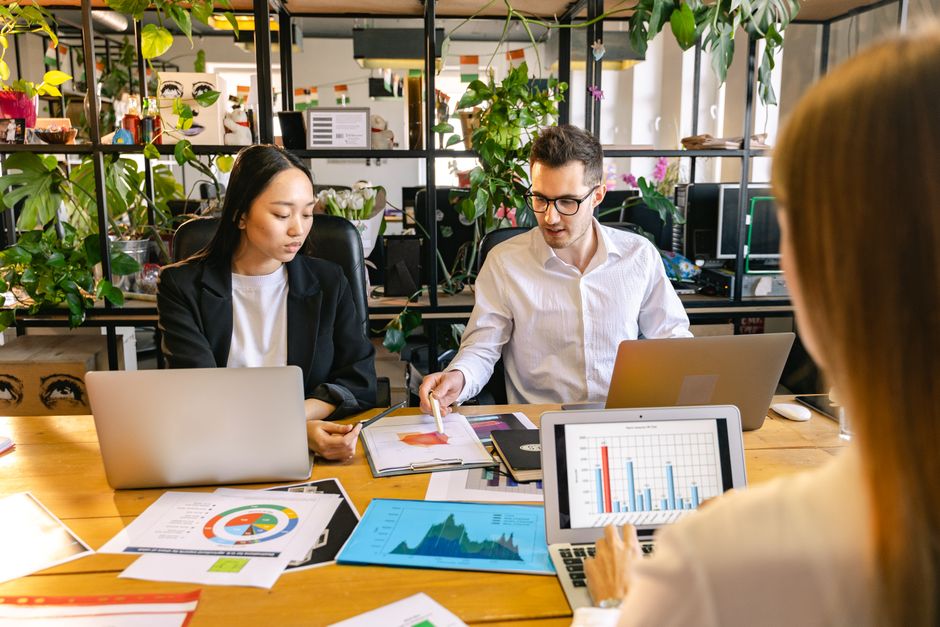 claude vs chatgpt marketing — A diverse group of professionals collaborating in a business meeting with laptops and char