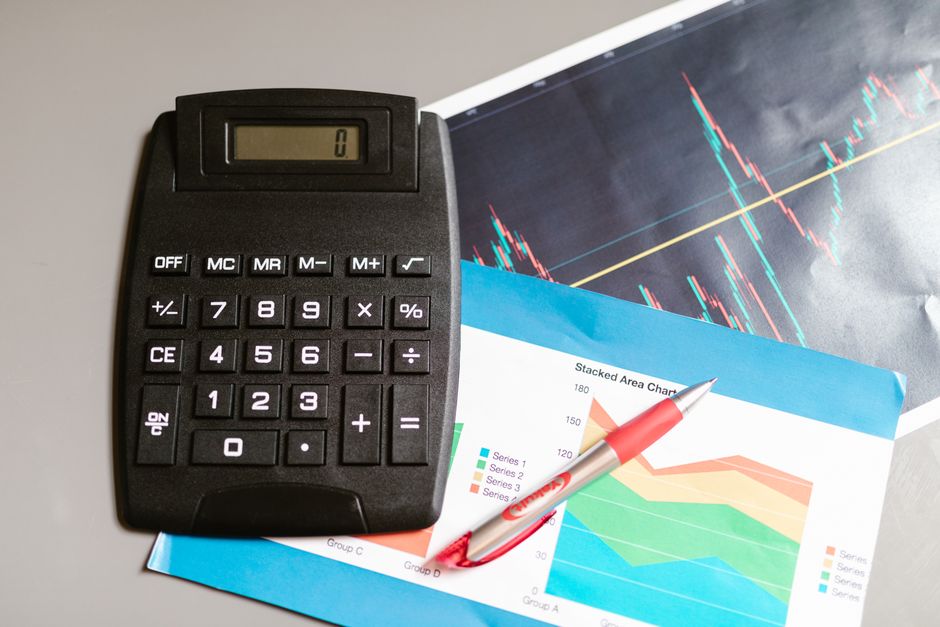 ราคาทำโฆษณา facebook — Calculator and pen on a desk with financial charts, showcasing analysis and business planning.