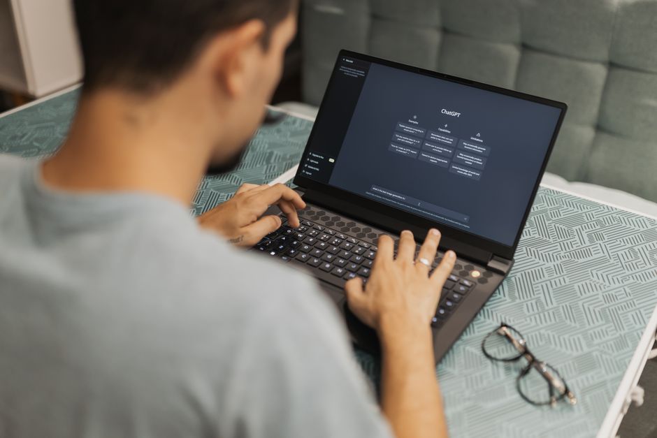 generative engine optimization — Man using laptop with AI interface, typing with focused attention. Indoors with eyewear