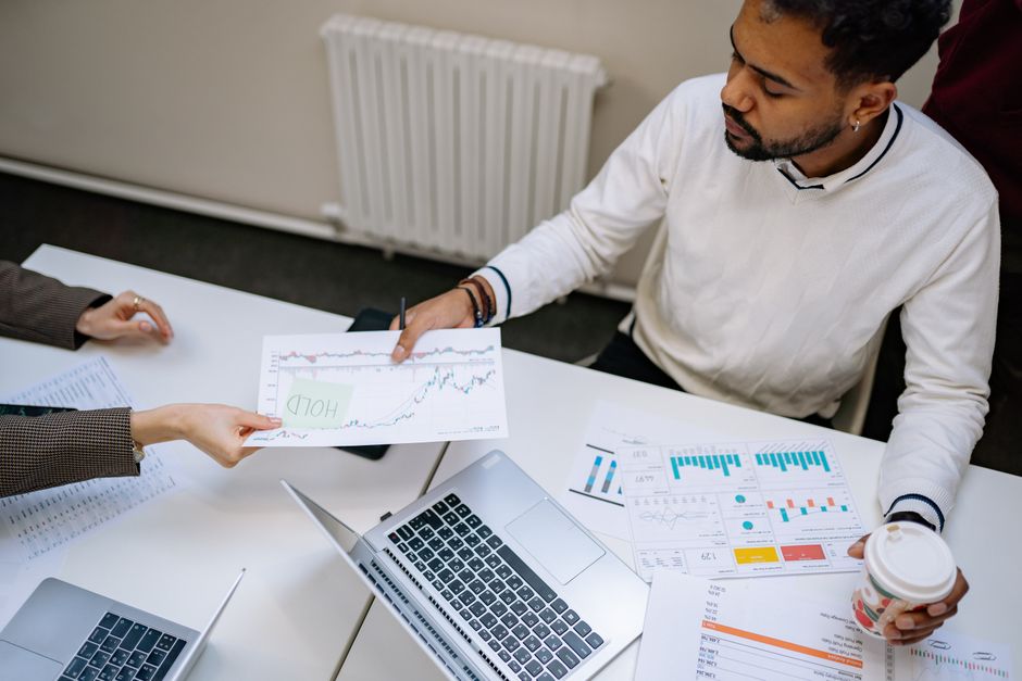 google ads vs facebook ads — Colleagues collaborating on financial charts and data during a business meeting indoors.