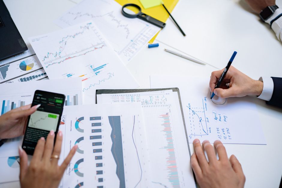 influencer marketing ไทย — Colleagues collaborating on financial charts and graphs using mobile and paper documents in t