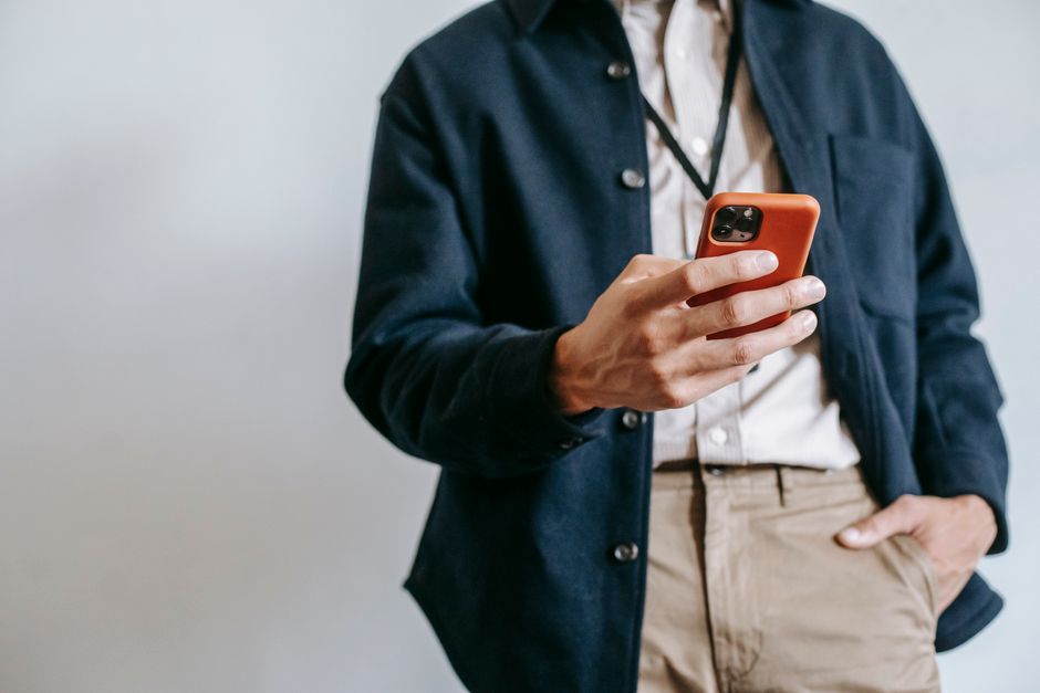 line oa line ads — Low angle of crop unrecognizable male manager in trendy outfit and name badge messaging on mobile pho