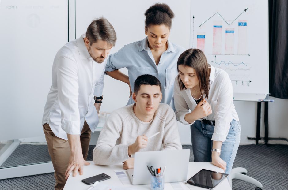 marketing dashboard — Group of professionals collaborating on a project with graphs in an office setting.