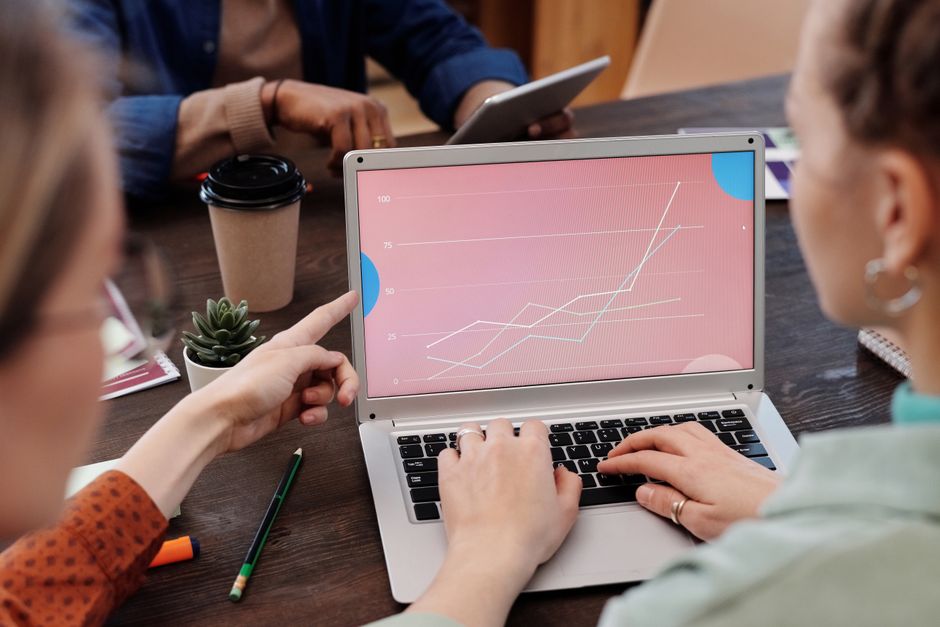 martech analytics tracking — Office workers collaboratively reviewing data trends on a laptop during a meeting.