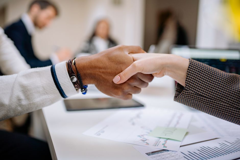 offline conversion — Diverse business professionals exchanging handshake in an office environment, symbolizing agreement