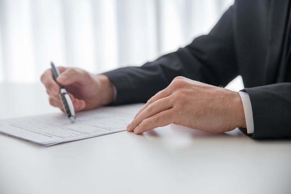 rfp template agency — Businessman signing important documents at office desk.