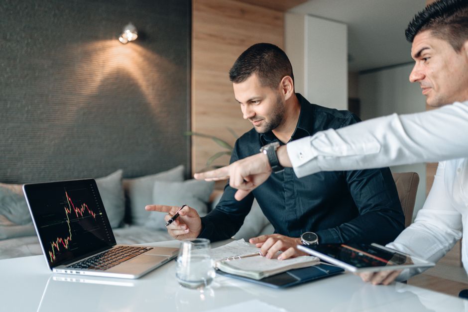 tiktok creator marketplace — Two businessmen reviewing financial data on a laptop indoors, analyzing market trends.