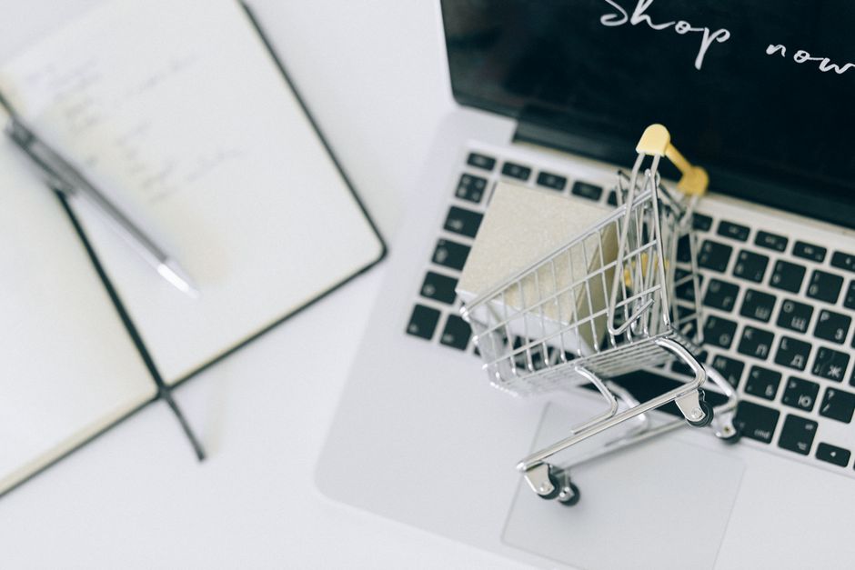 abandoned cart email — Creative depiction of online shopping with a miniature cart on a laptop keyboard.