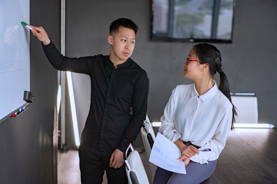 abm คือ — Professional team discussing ideas at a whiteboard in a modern office setting.