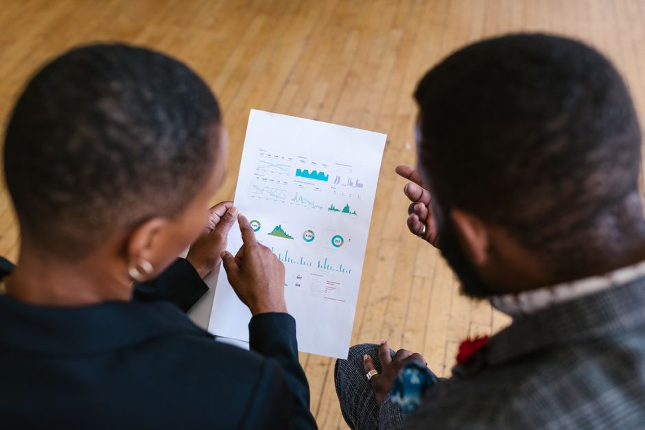looker studio b2b — Two business colleagues examining a document with charts in an office setting.