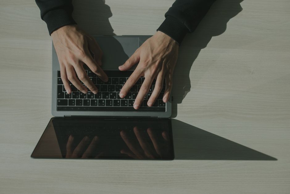 onboarding email — Overhead shot of hands typing on a laptop, showcasing technology and internet usage.