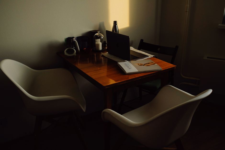 pricing page design — A warm, dark-toned home office with a wooden table and contemporary chairs. Includes a laptop, mag