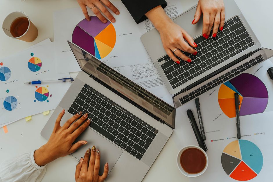segment vs rudderstack — Overhead view of a team analyzing graphs and charts using laptops at a meeting.