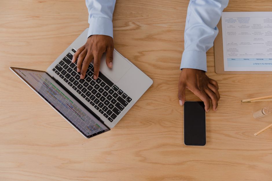 spf dkim dmarc คือ — Top view of a workspace featuring hands using a laptop and smartphone on a wooden desk.
