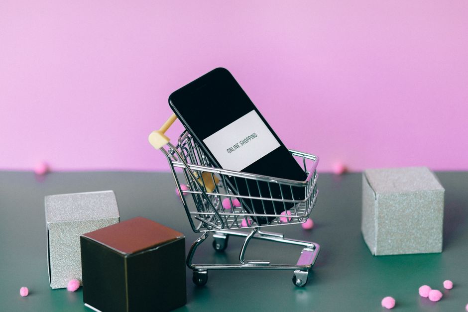 tiktok shop ตั้งค่า — A smartphone with a shopping cart depicting the concept of online shopping in a colorful studio se