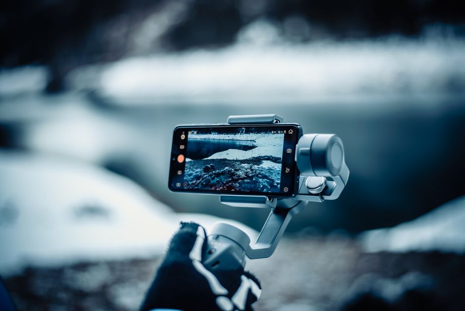 youtube shorts — A smartphone mounted on a stabilizer capturing a snowy winter scene outdoors.