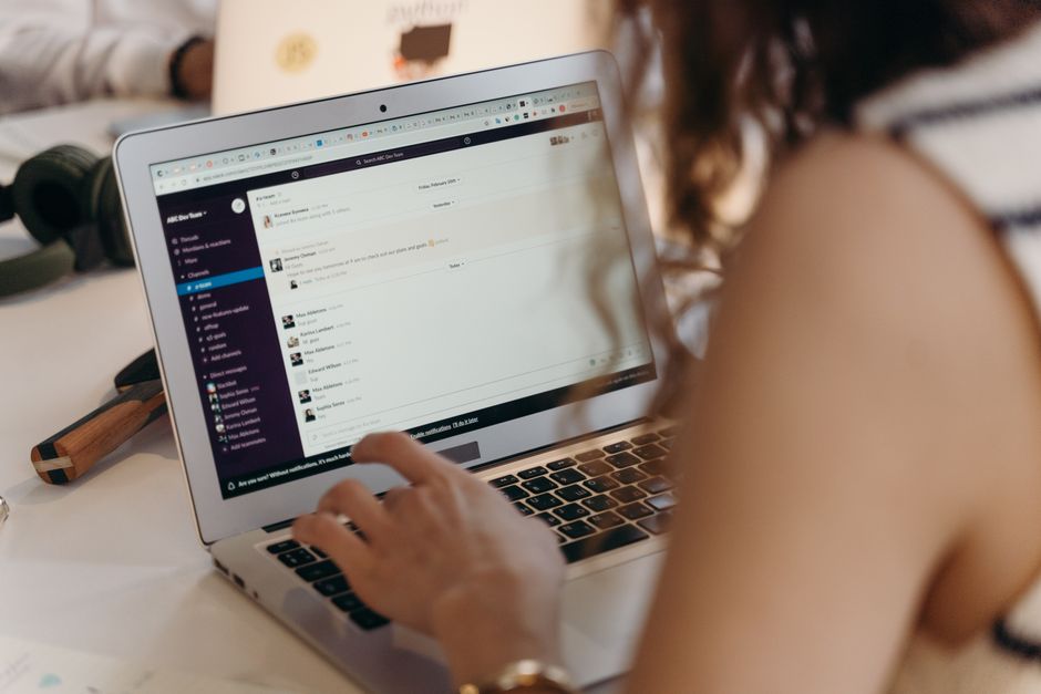 email drip campaign — A businesswoman typing on a laptop in an office setting, using Slack for communication.