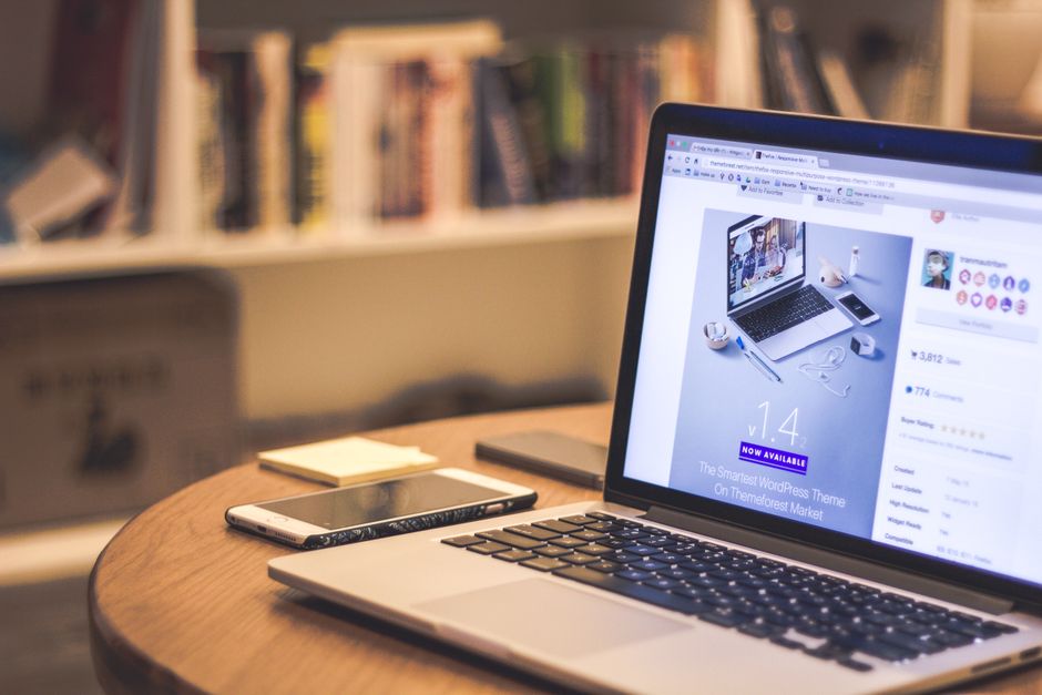 internal linking — A cozy modern workspace featuring a laptop displaying a website, a smartphone, and books on shelves.