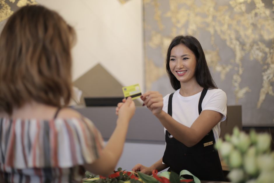 membership program — Florist smiling while accepting payment in a flower shop.