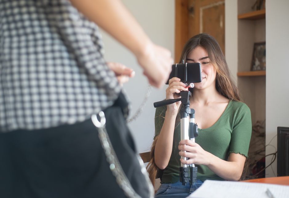 spark ads tiktok — A young woman vlogs indoors using a smartphone mounted on a tripod, capturing content creation.