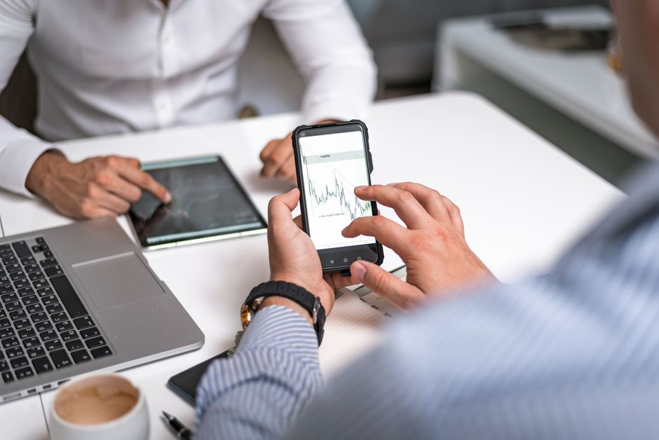 tiktok ads ราคา — Two business professionals analyzing market trends on digital devices in an office setting.