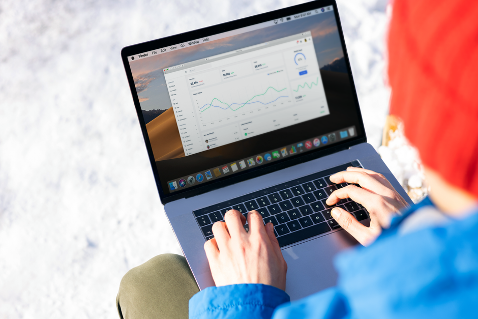 cohort analysis คือ — A person in a blue jacket analyzing business analytics on a laptop outdoors during winter.